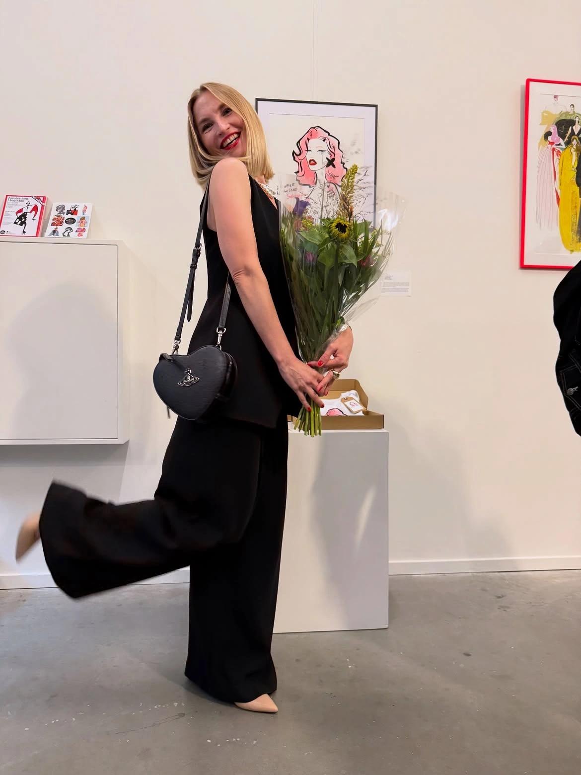 Artist holding flowers beside her work at Amsterdam Modestad.